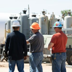 Profissionais em ambiente industrial utilizando capacetes de segurança durante uma reunião técnica