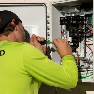 Profissional realizando serviço em painel elétrico com vestimenta de alta visibilidade
